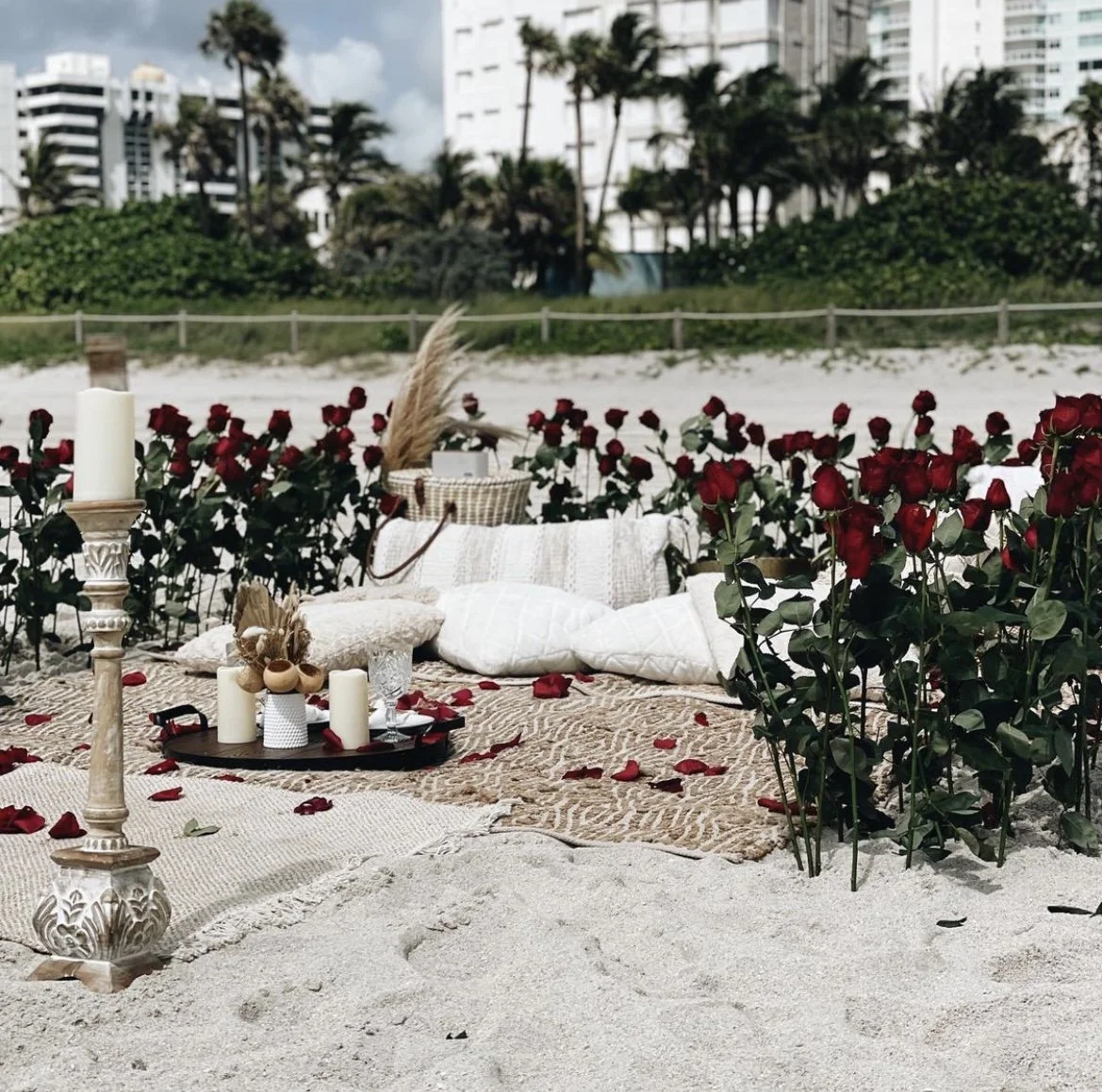 Romantic beach picnic setup Miami luxury candles roses champagne couple